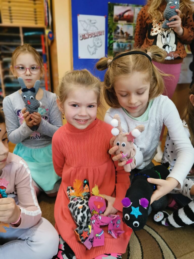 Dzieci prezentują zabawki, które wykonały ze skarpetek i rękawiczek. 