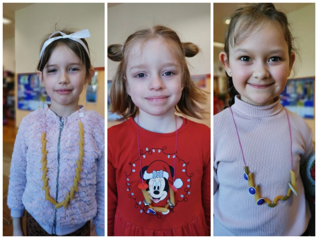 Dziewczynki prezentują swoje naszyjniki, wykonane z makaronu i guzików.